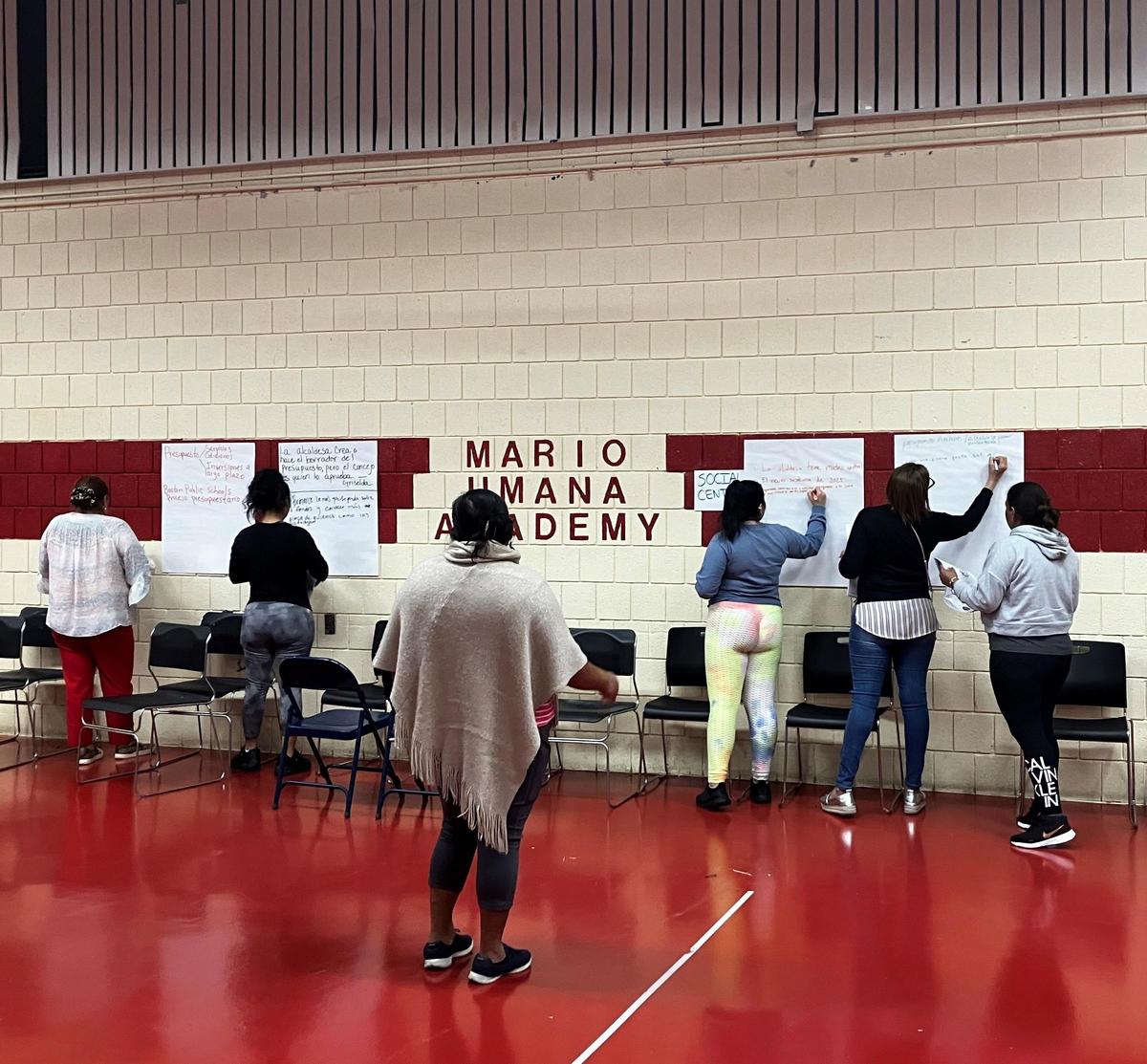 Participants write on large sheets of paper attached to the wall in a gymnasium