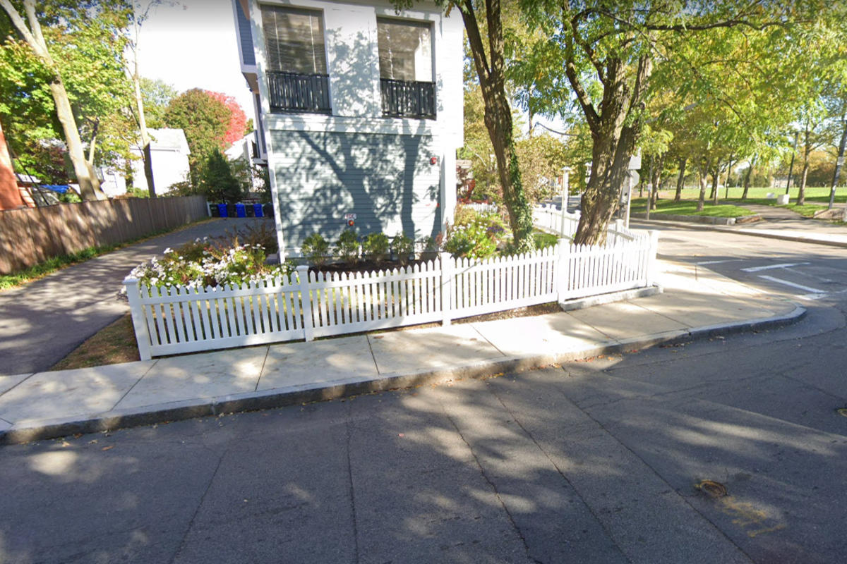 Photo of a newly built concrete sidewalk with a house in the background.